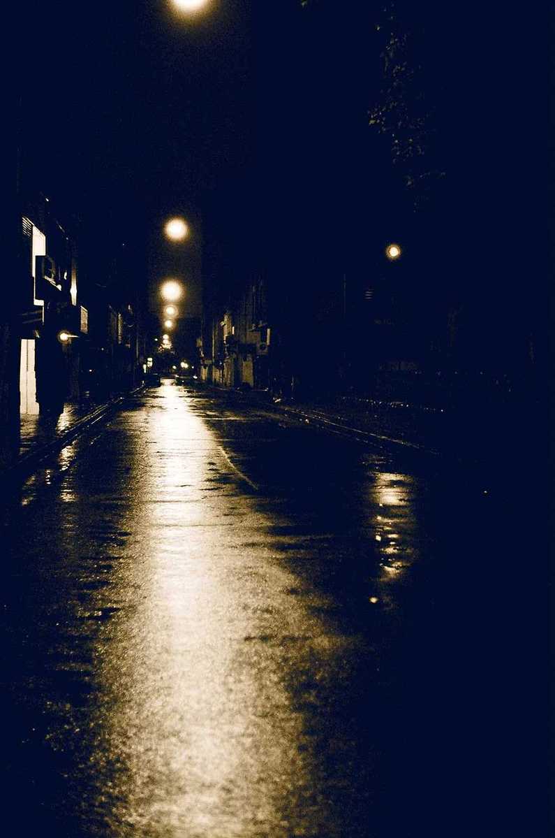 a night time picture of street lamps on a rainy day