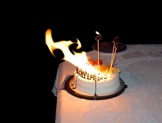 a cake topped with lots of candles and some flames