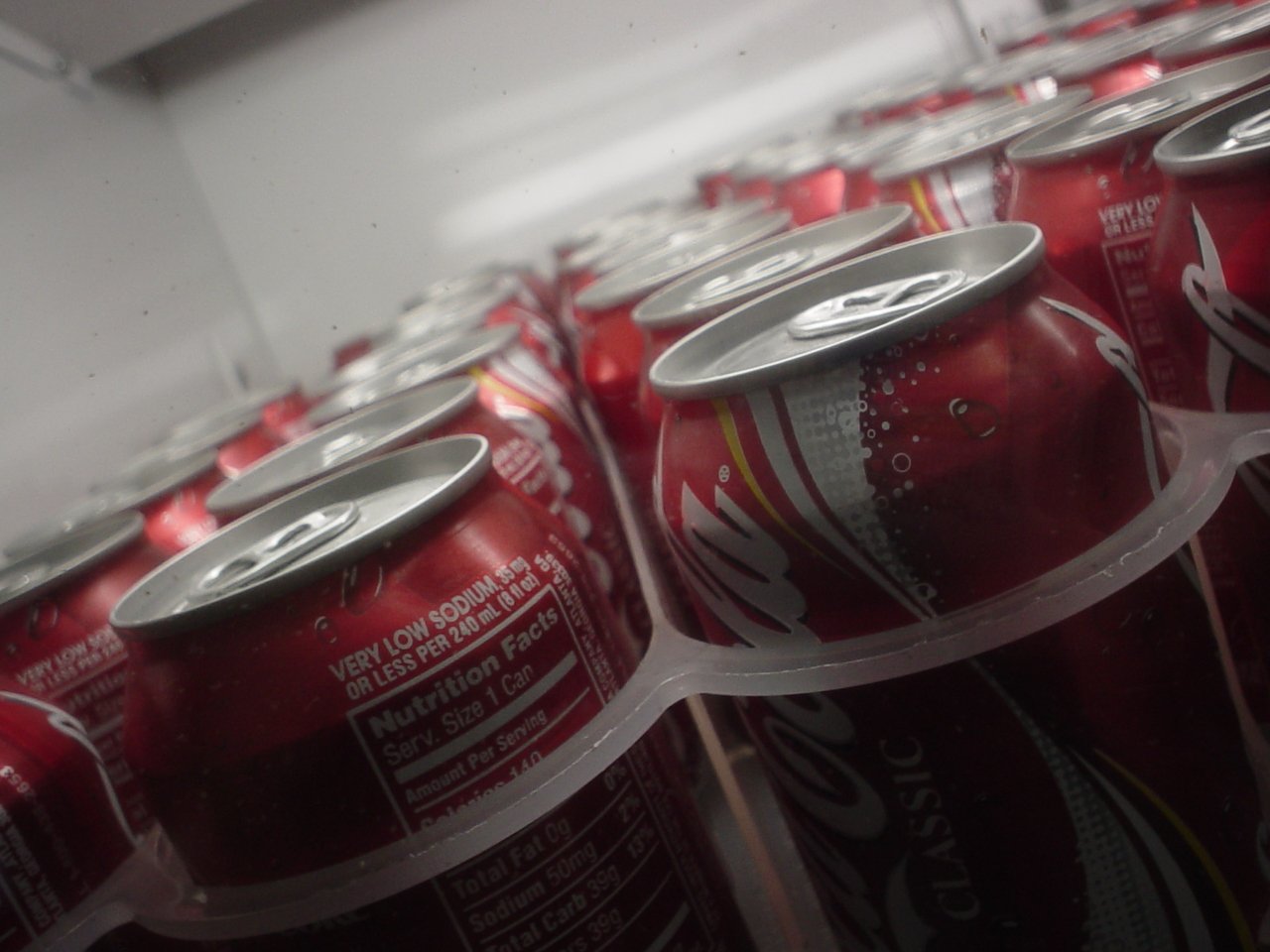 many red soda bottles are lined up in rows