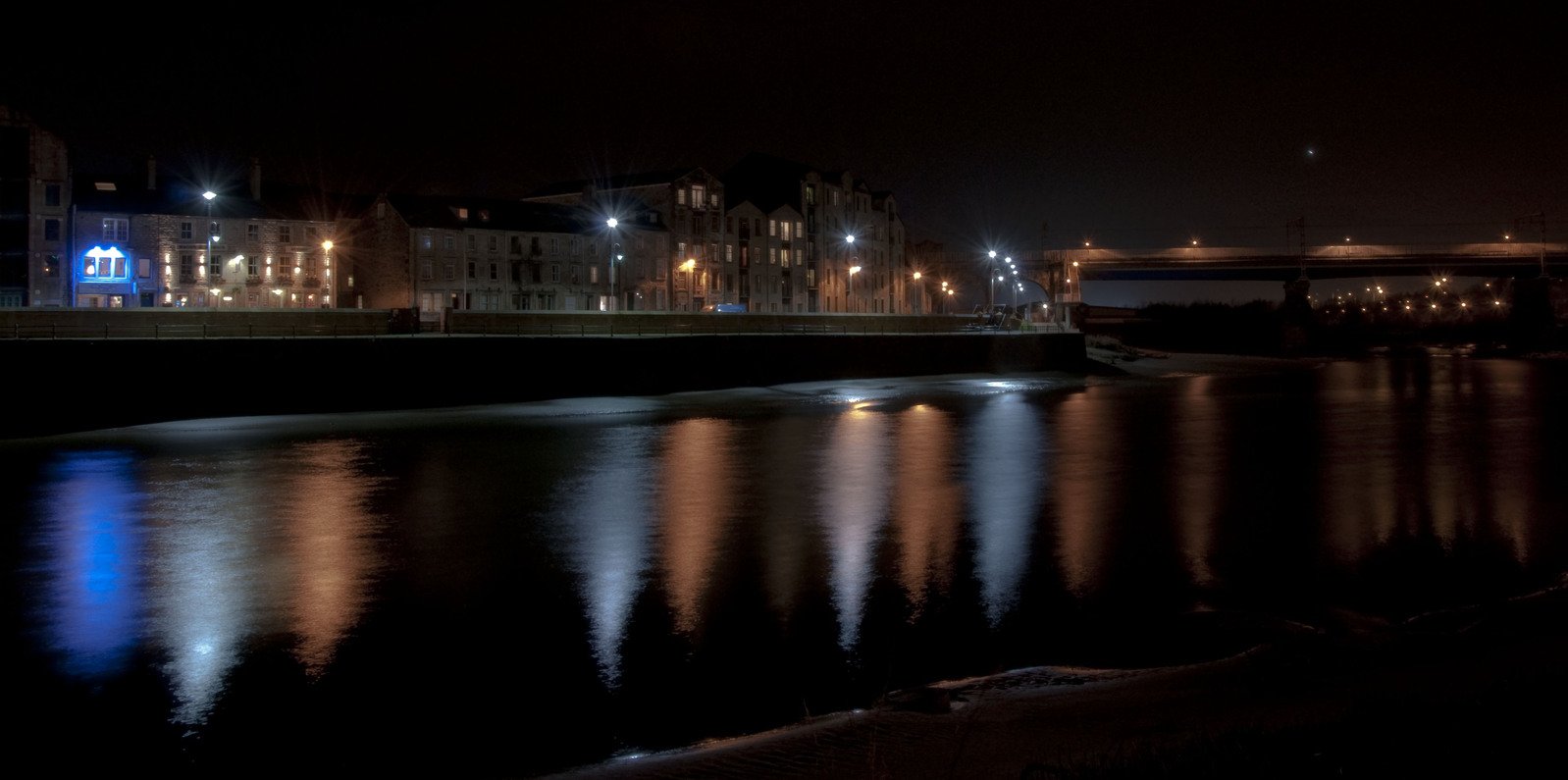 some lights are shining on the water at night