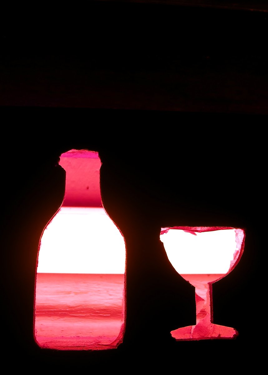 two bottles, wine glass and bottle light with water in background