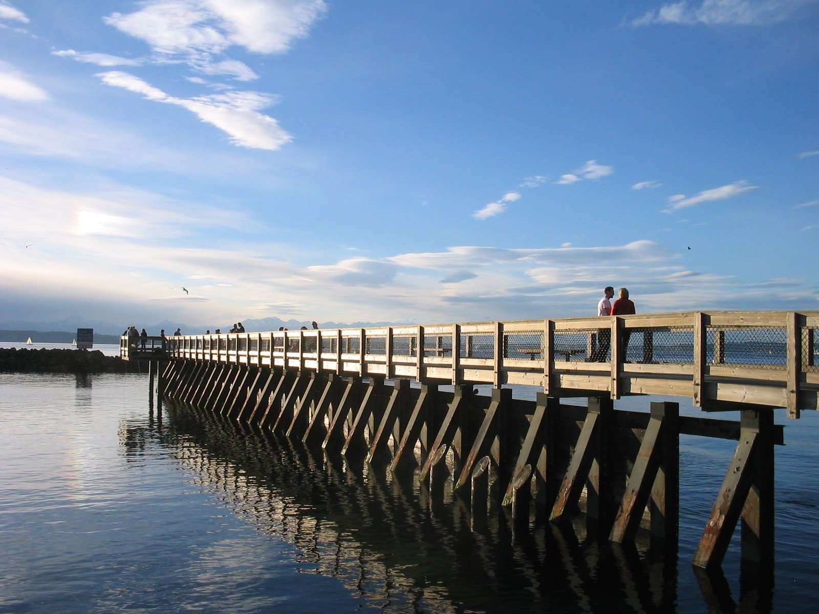 people standing on the end of a pier looking out to sea