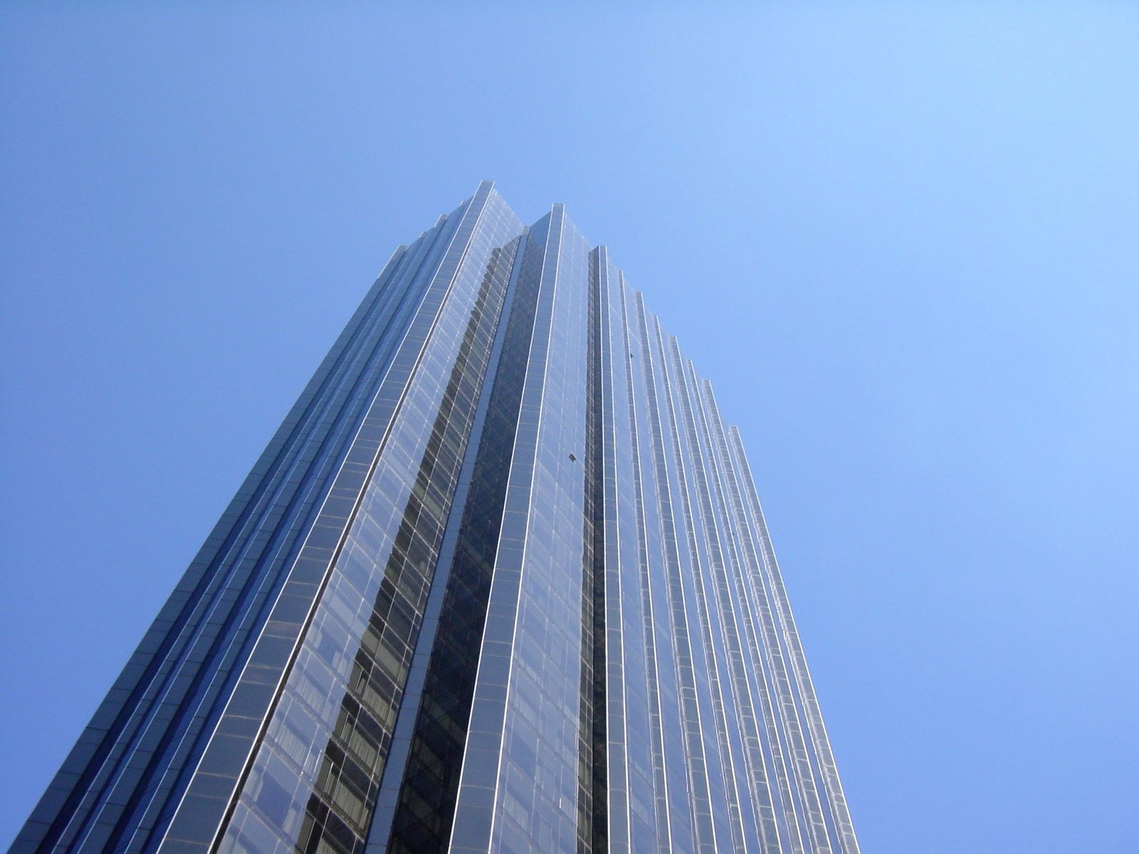 the view up at a tall, glass skyscr with many windows