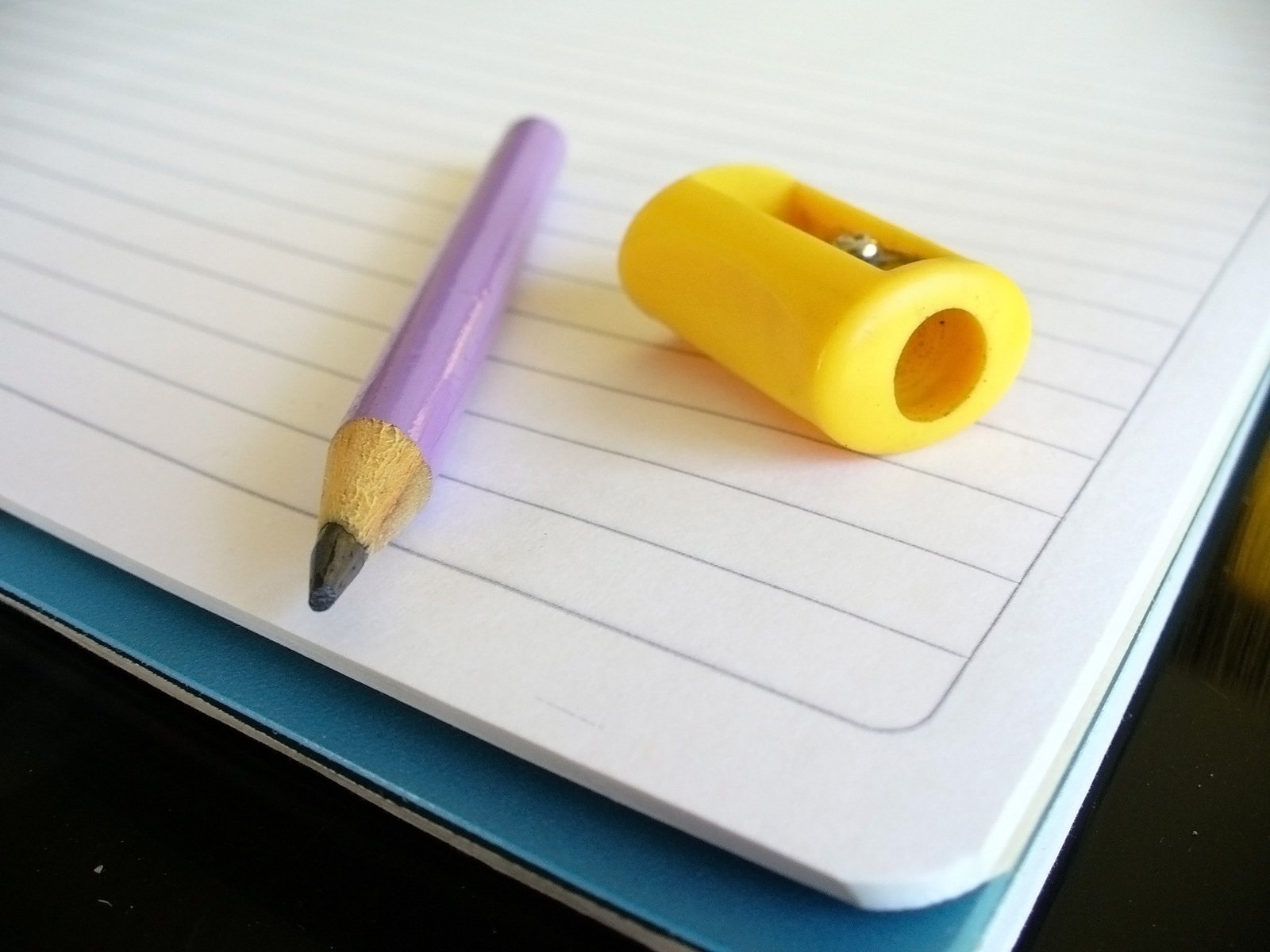 a yellow pen on top of a notebook next to a purple eraser