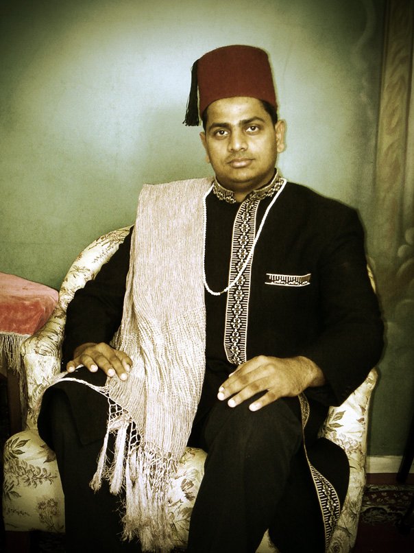 a man sitting in an ornate chair wearing a traditional indian garb