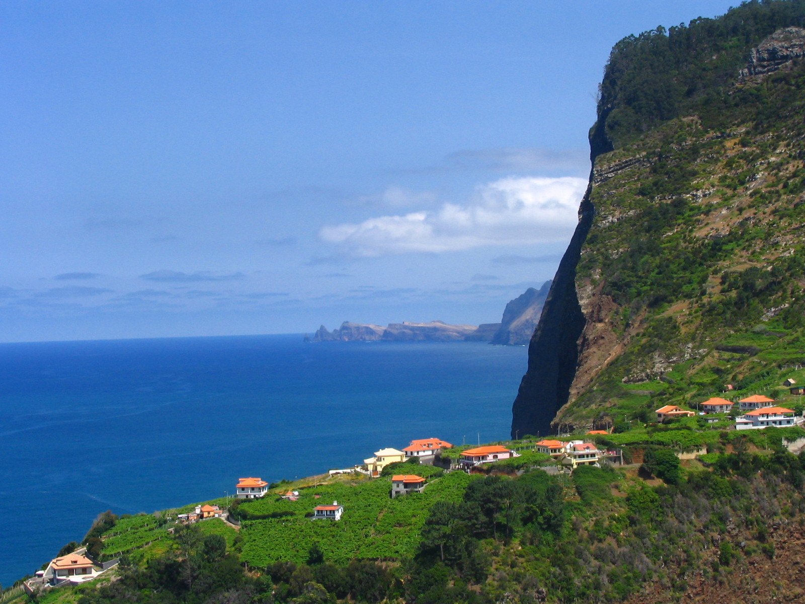 the mountains surrounding houses next to the water