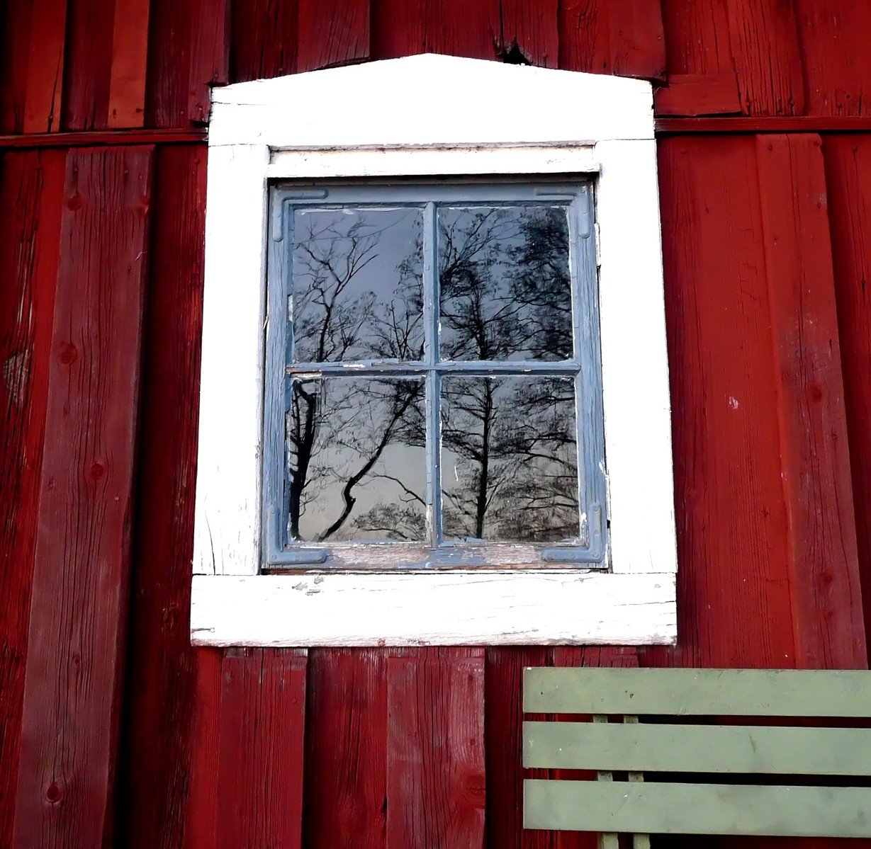 a wooden bench and a window in front of a red building