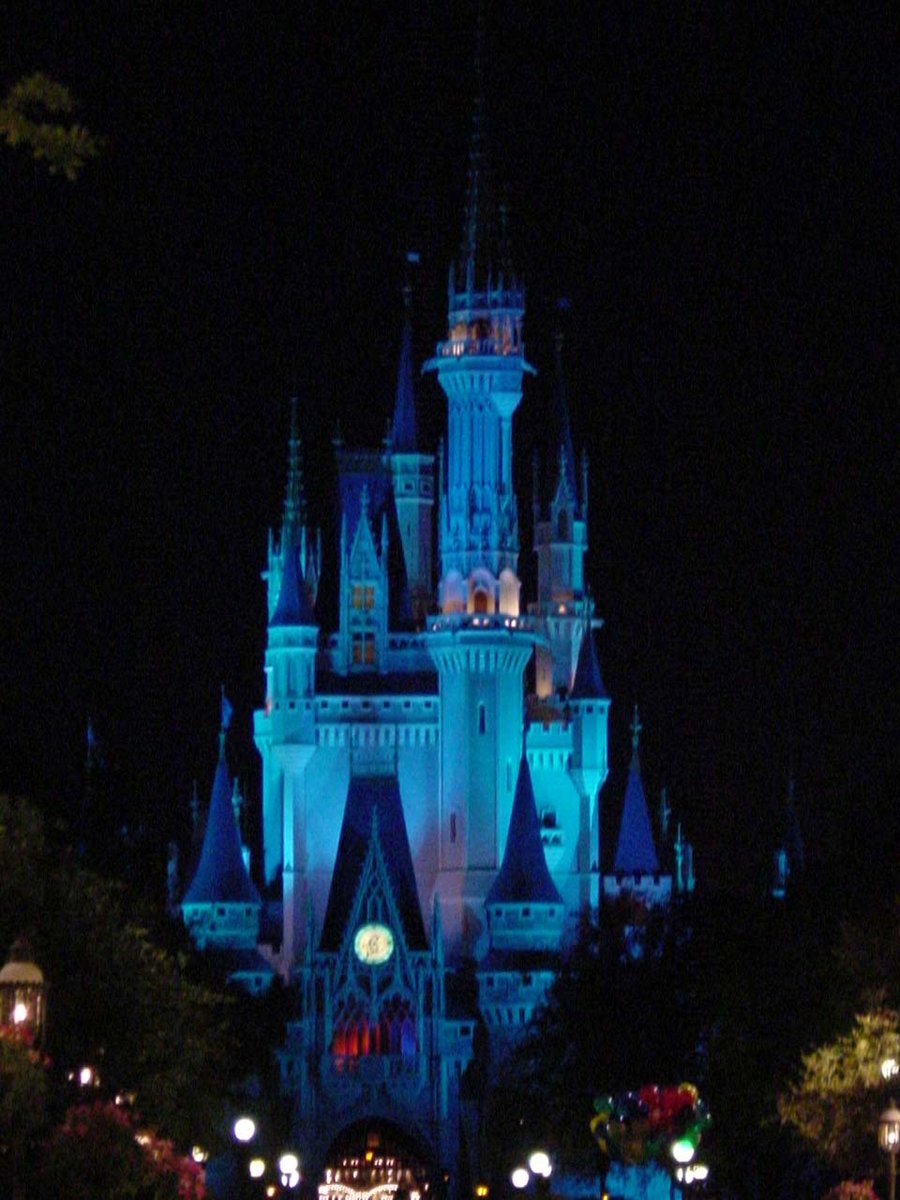 a castle lit up with blue lights and a crowd