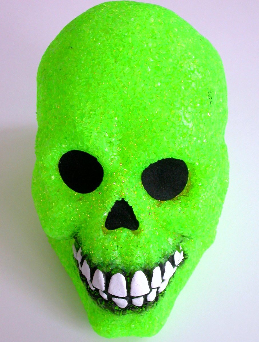 a green skull with fangs is on a white table
