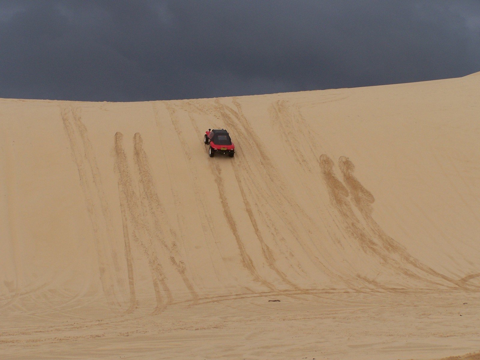 a vehicle driving down a very steep desert hill