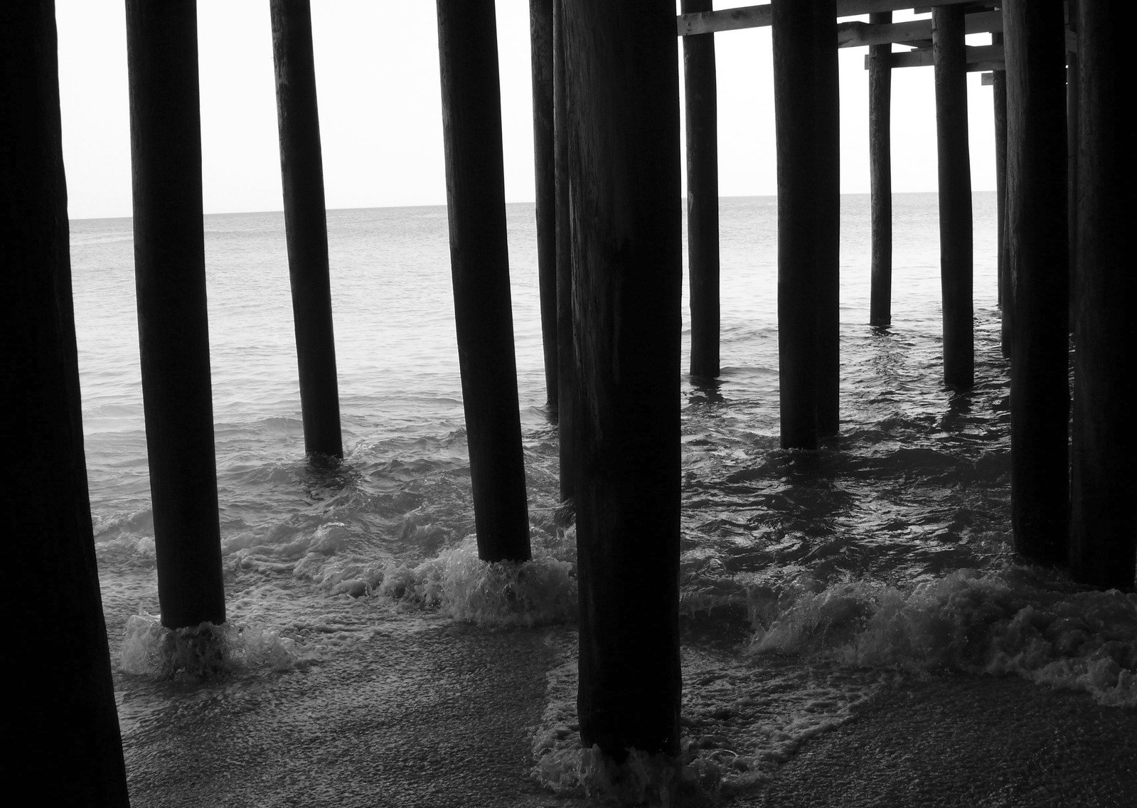 black and white pograph of a pier on the ocean