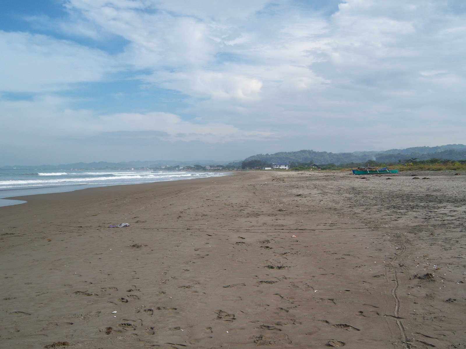 a deserted beach with a body of water and several buildings in the distance