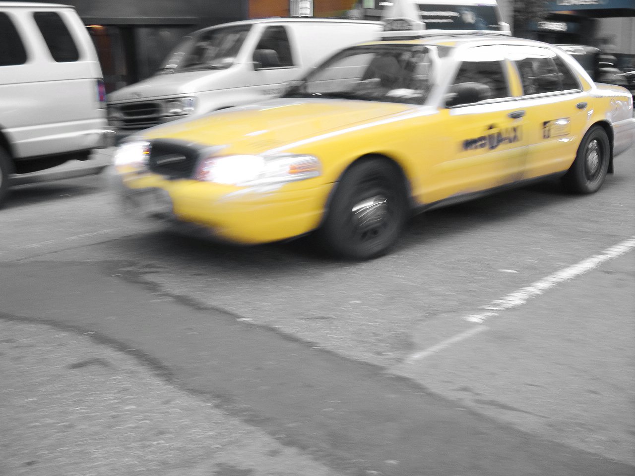 a yellow taxi cab speeding down a busy street