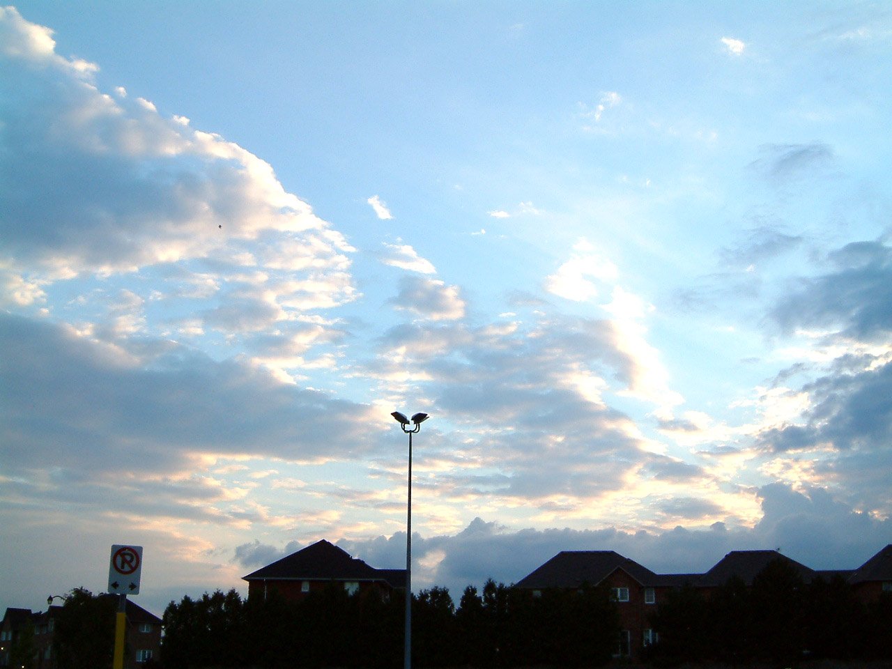 a streetlight against the evening sky by residential homes