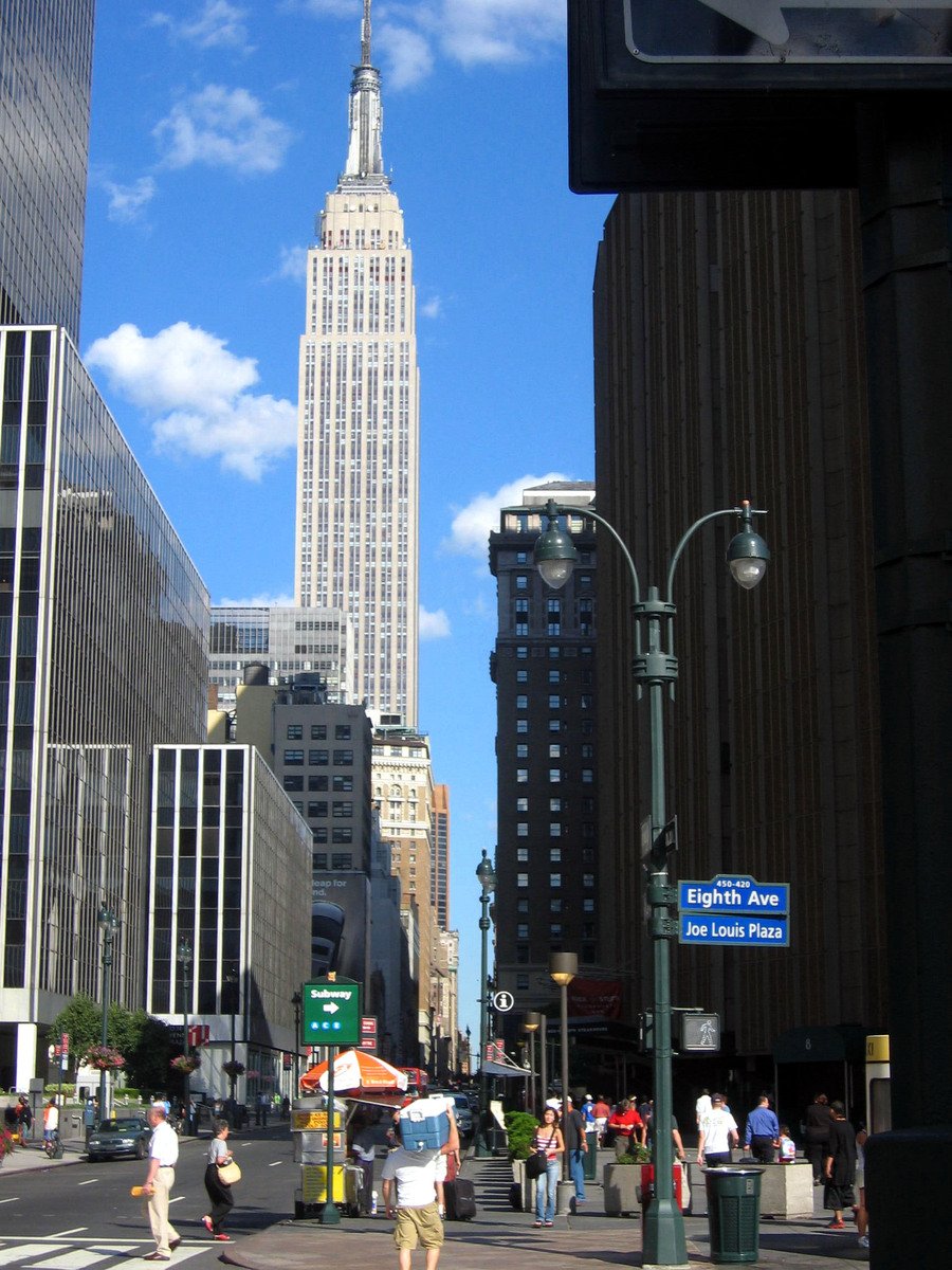 a street scene with people, buildings and people walking on the sidewalk