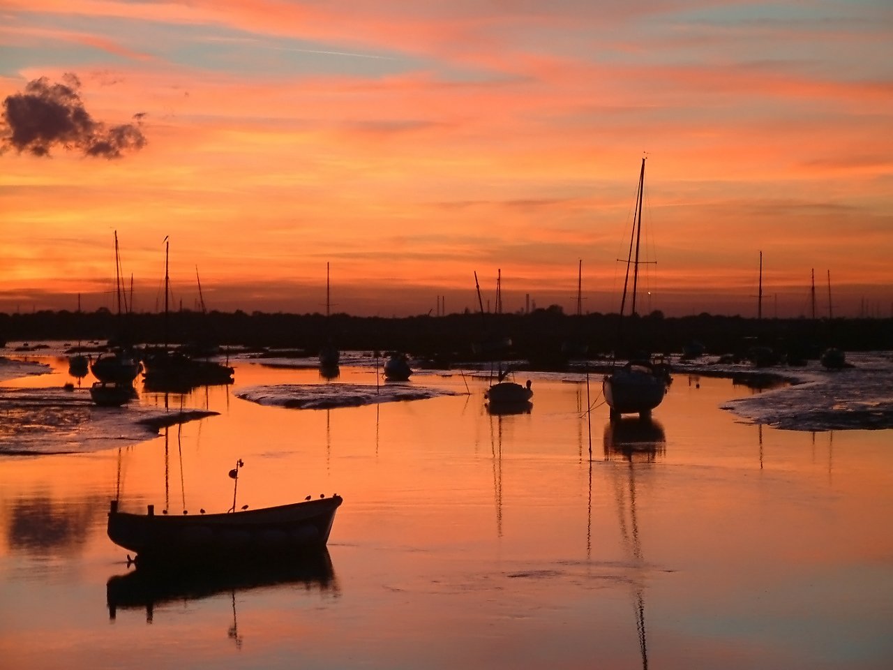 a sunset over small sailboats in the water