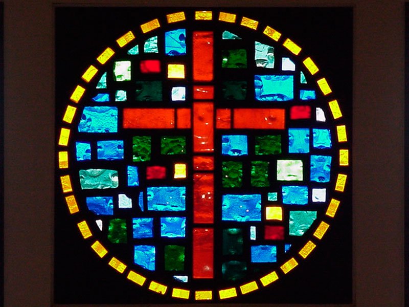 a cross on a stained glass in the window