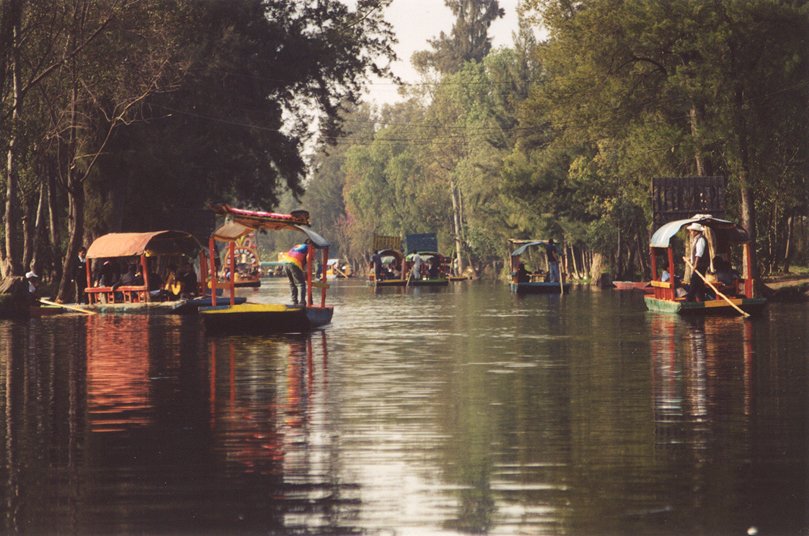 the boats are traveling on the river as people walk by