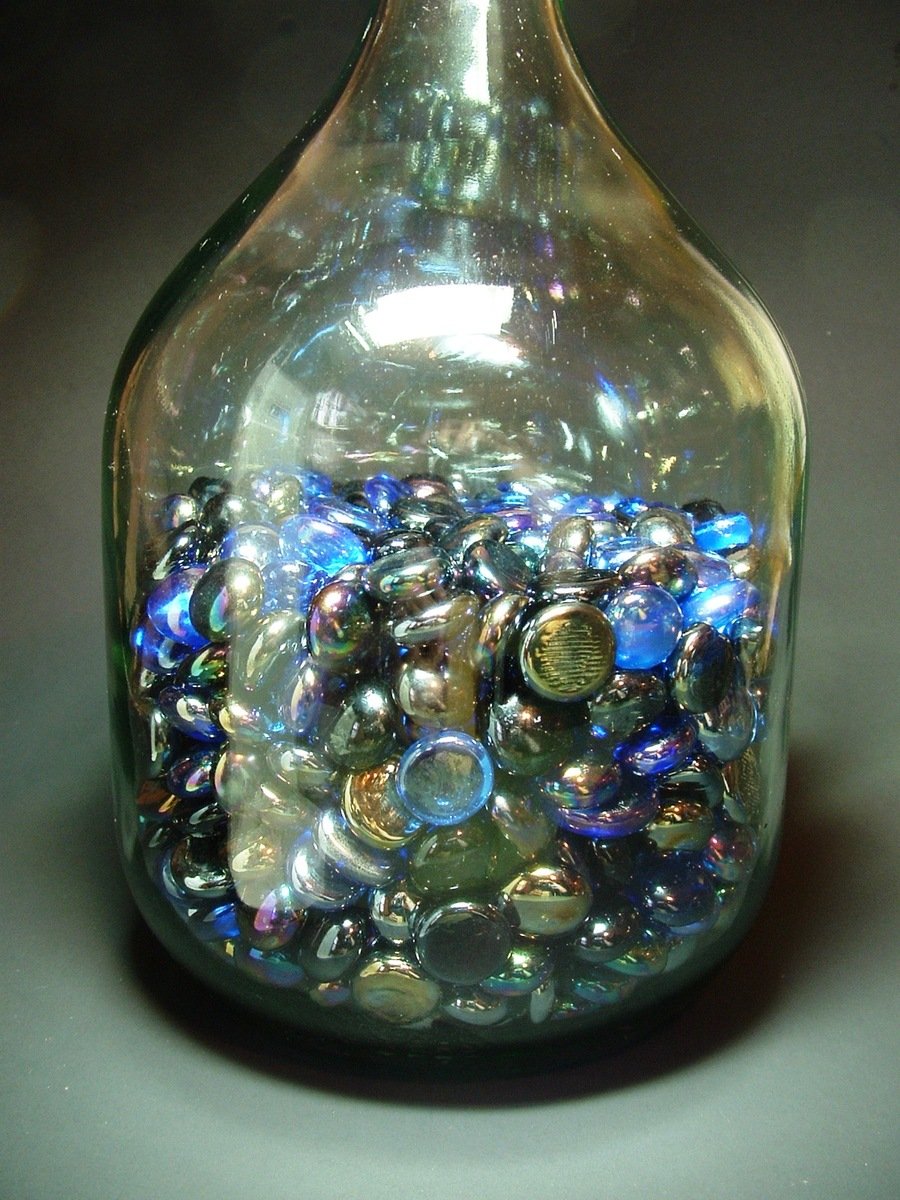 a clear glass bottle full of lots of silver coins