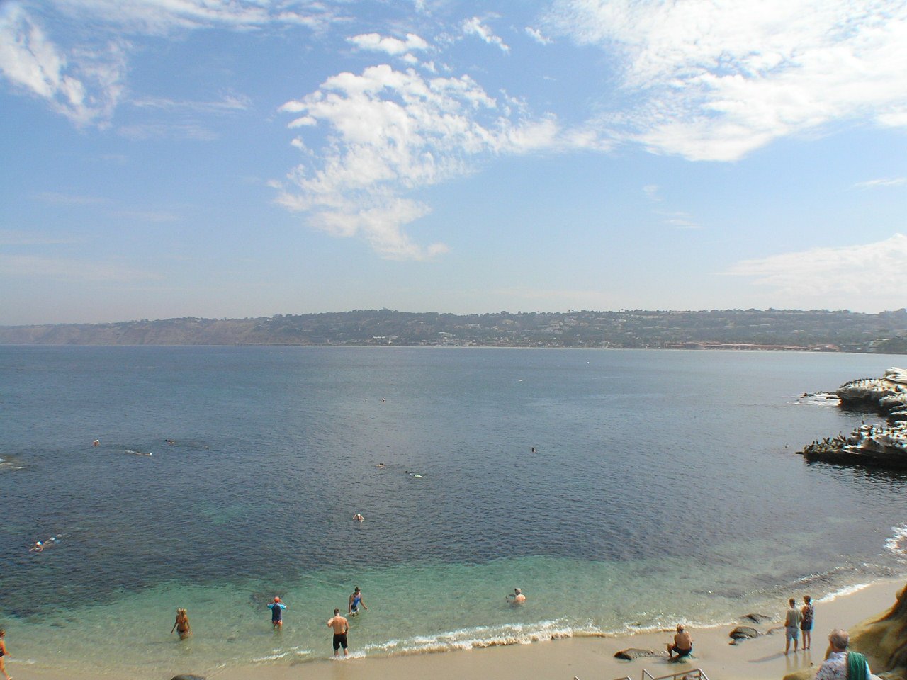 the beach with people and swimmers on a sunny day