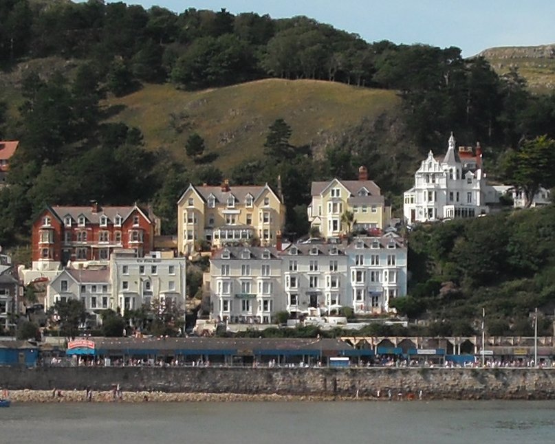 the coast with houses is shown in front of a hill