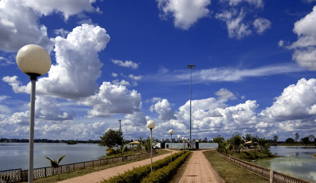 a cobblestone path beside the water on an sunny day