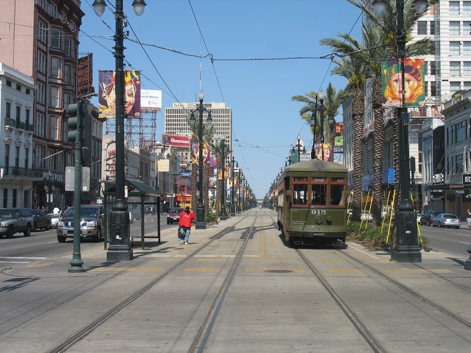 a trolley driving down a street with tall buildings in the background