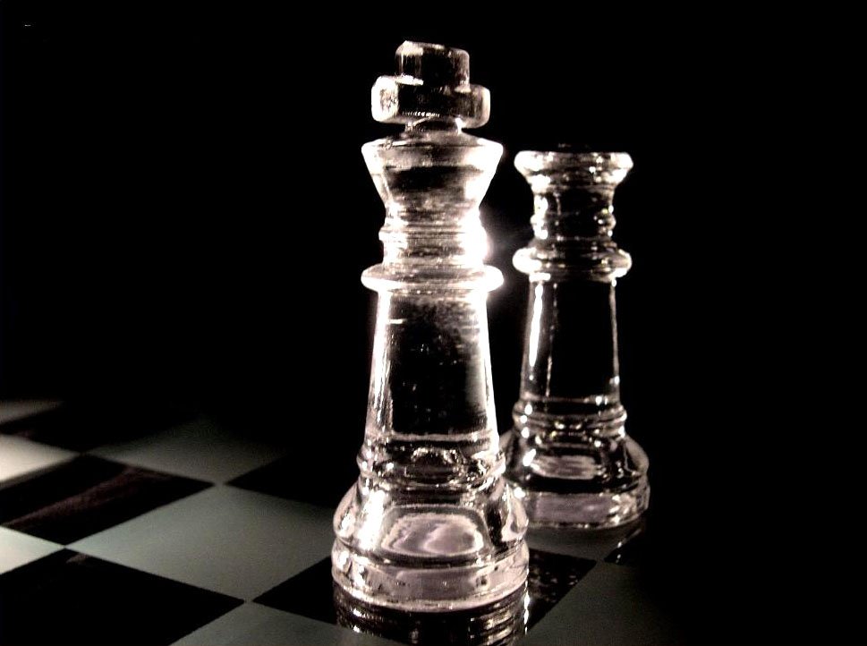 a couple of glass chess pieces on top of a checkered floor