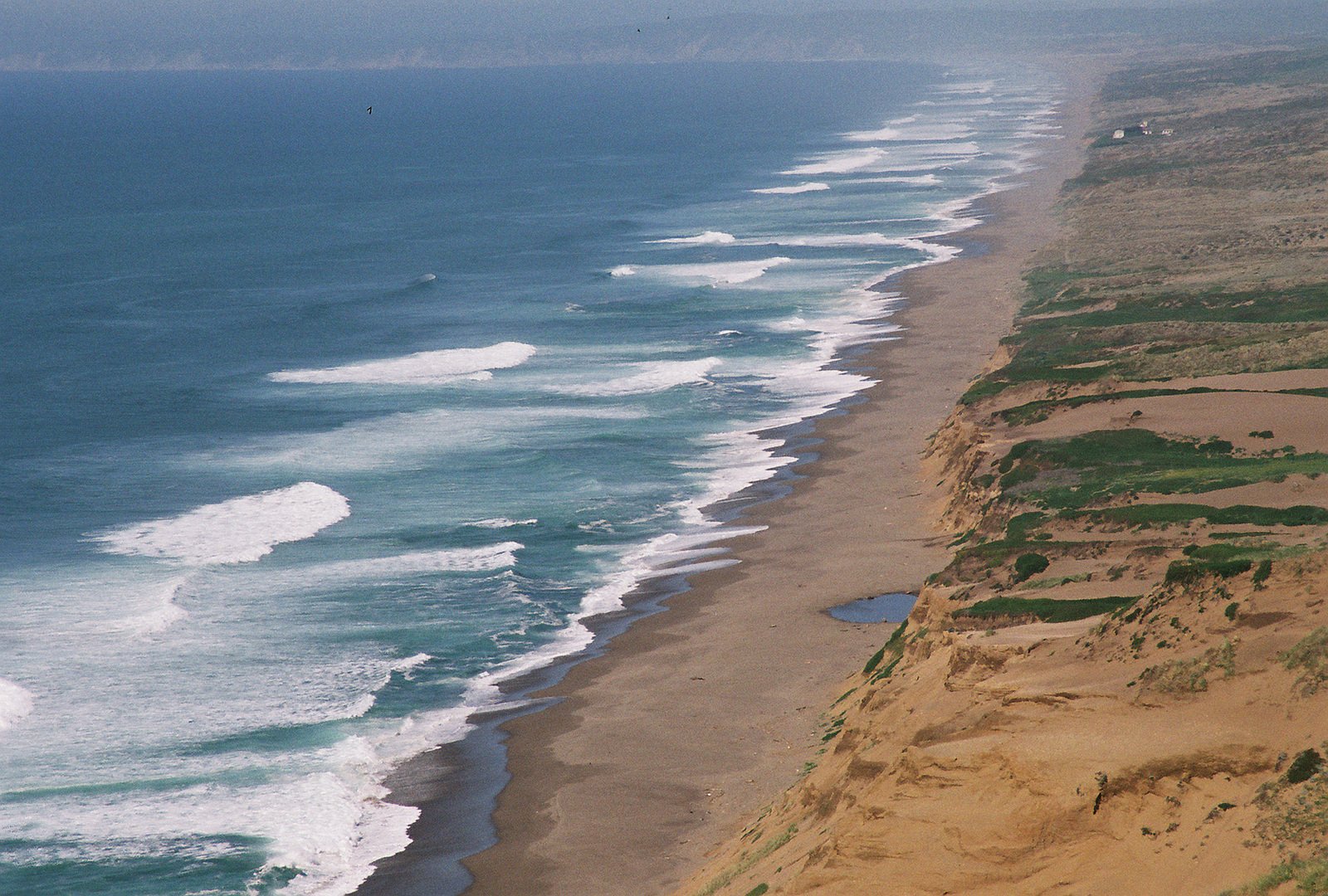 an ocean view with a road running next to it and the beach in the background