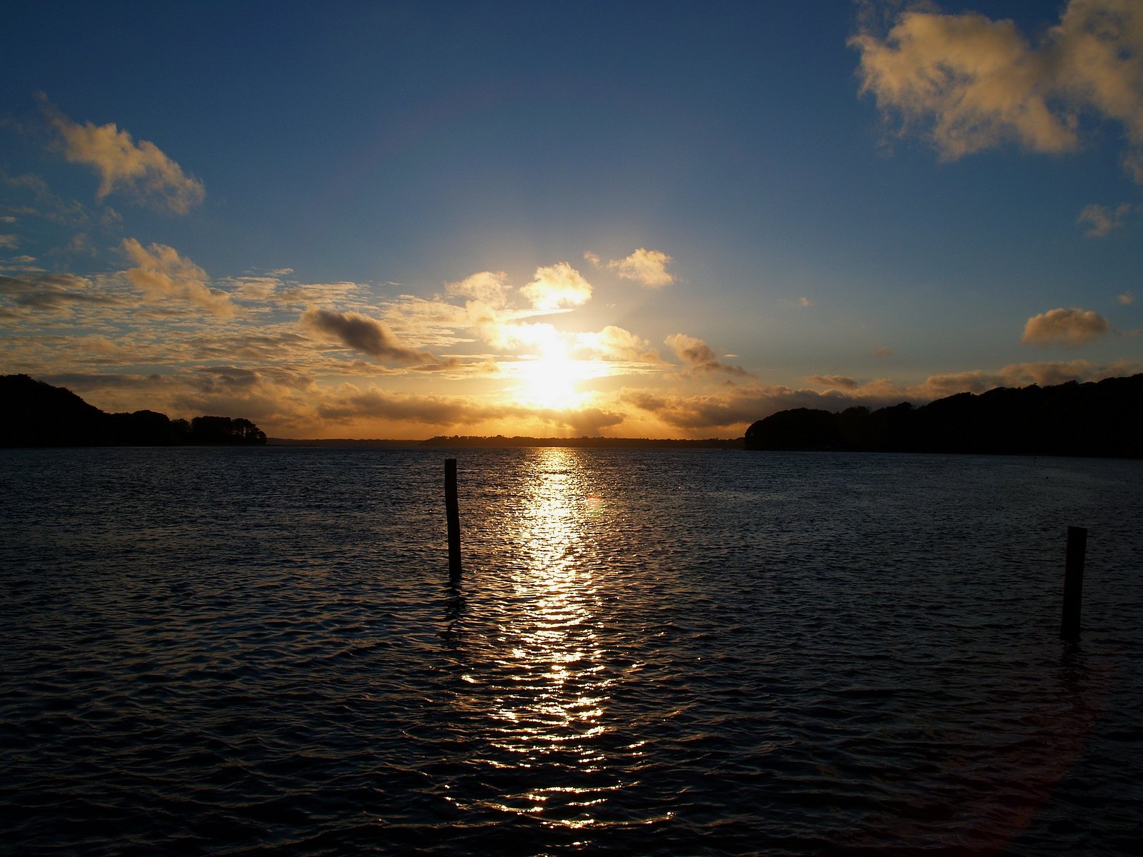 a body of water with a boat out at sea under a bright sun