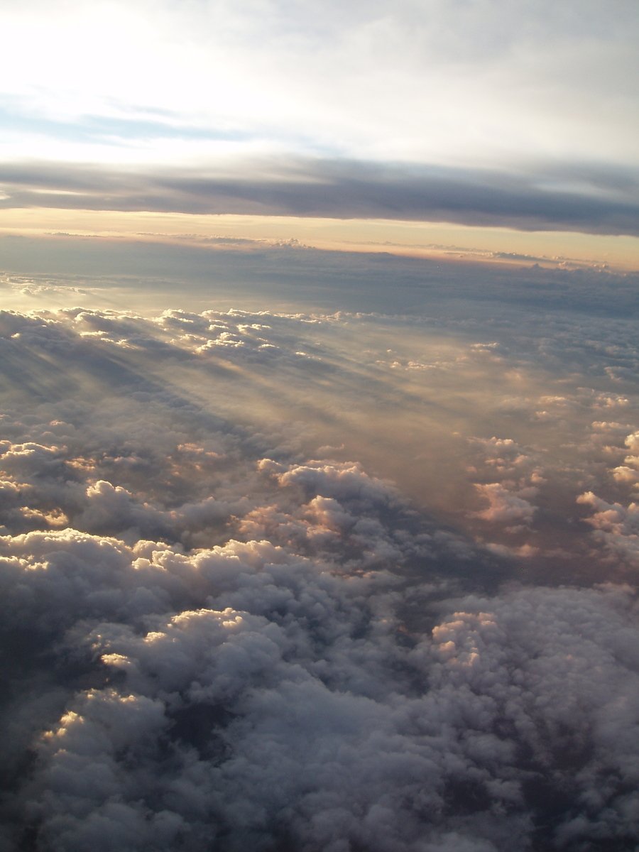 view out an airplane window as clouds fly through