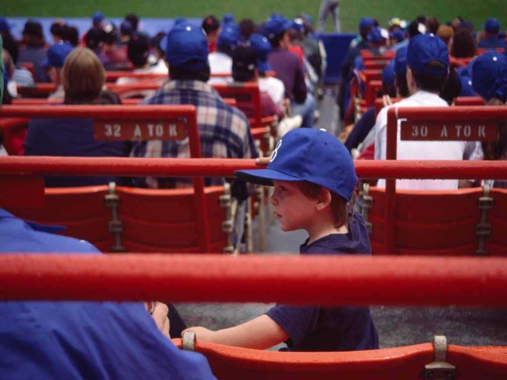 a boy with a hat sitting in front of a red bench