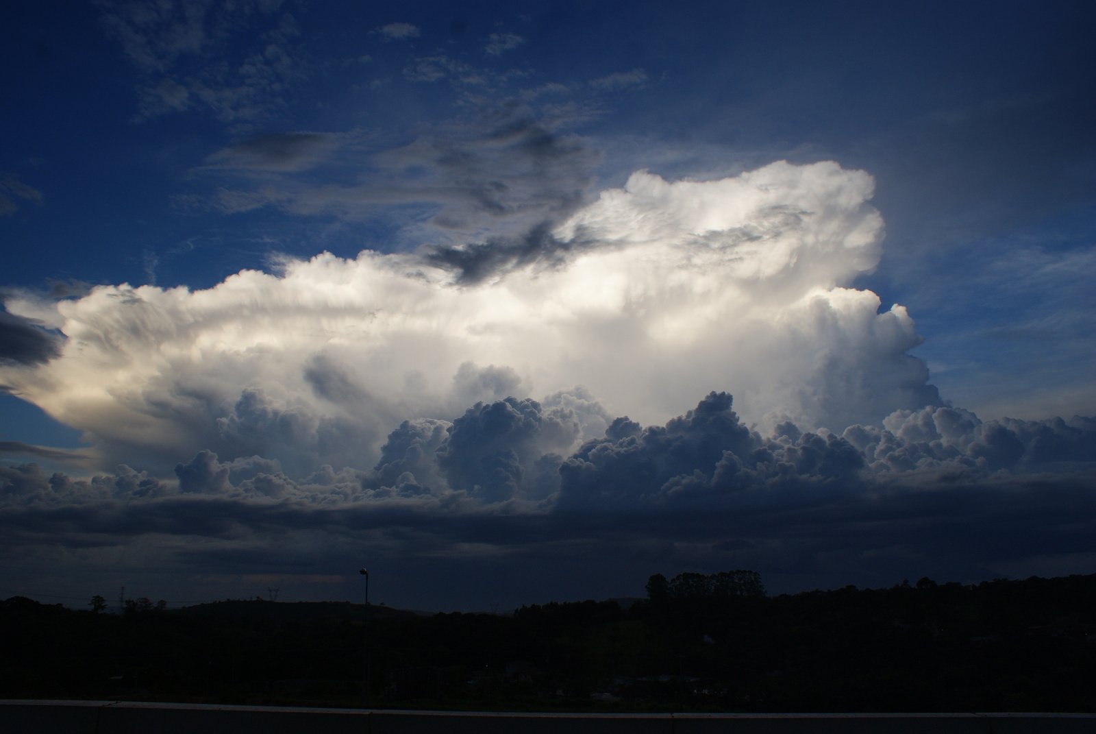 a large cloud above an ocean next to a city