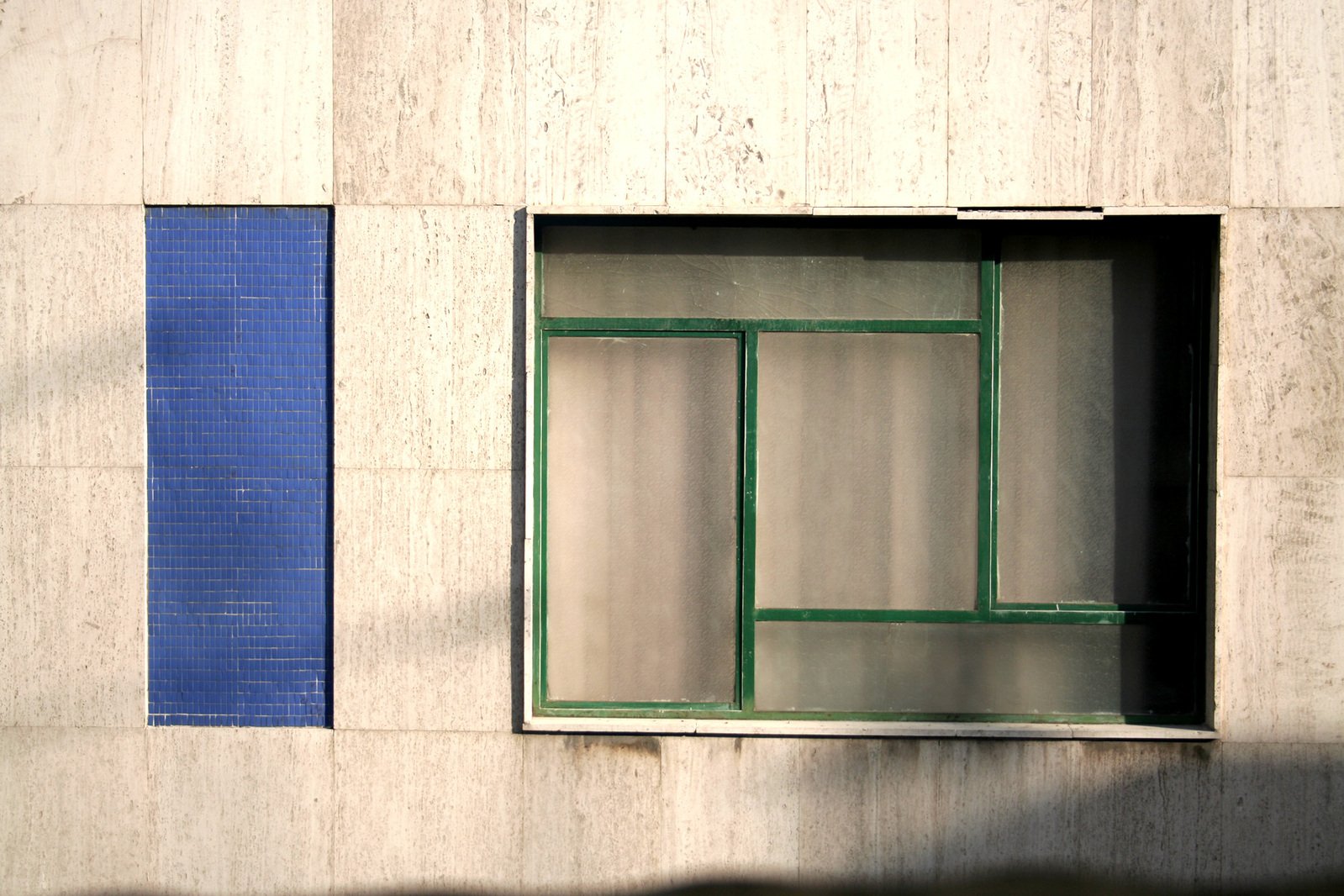 a white wall with two green windows on it