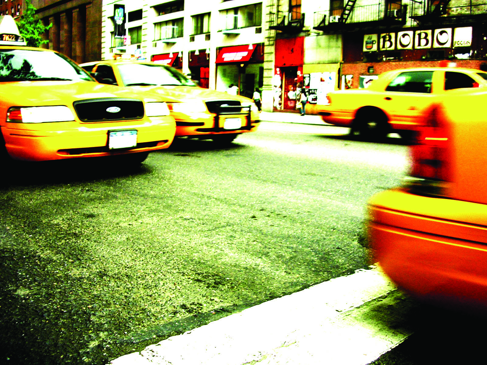 a yellow cab driving down the middle of a street