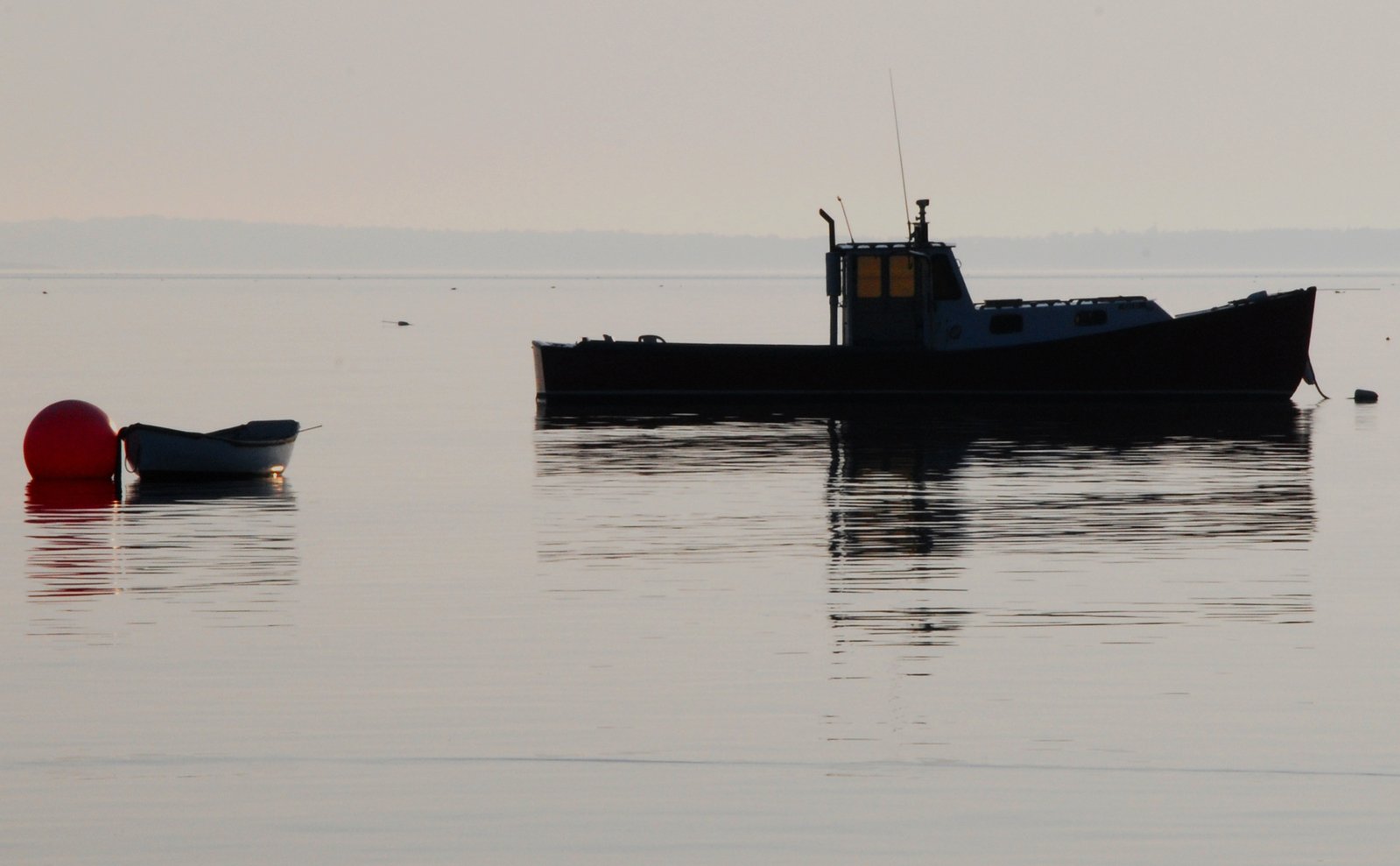 a small boat floats near an orange buoy