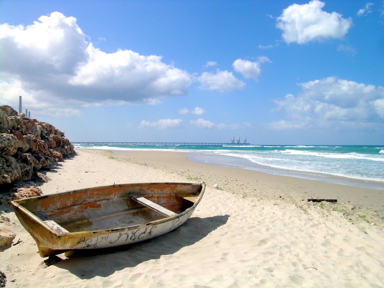 an abandoned boat sitting in the sand on the beach