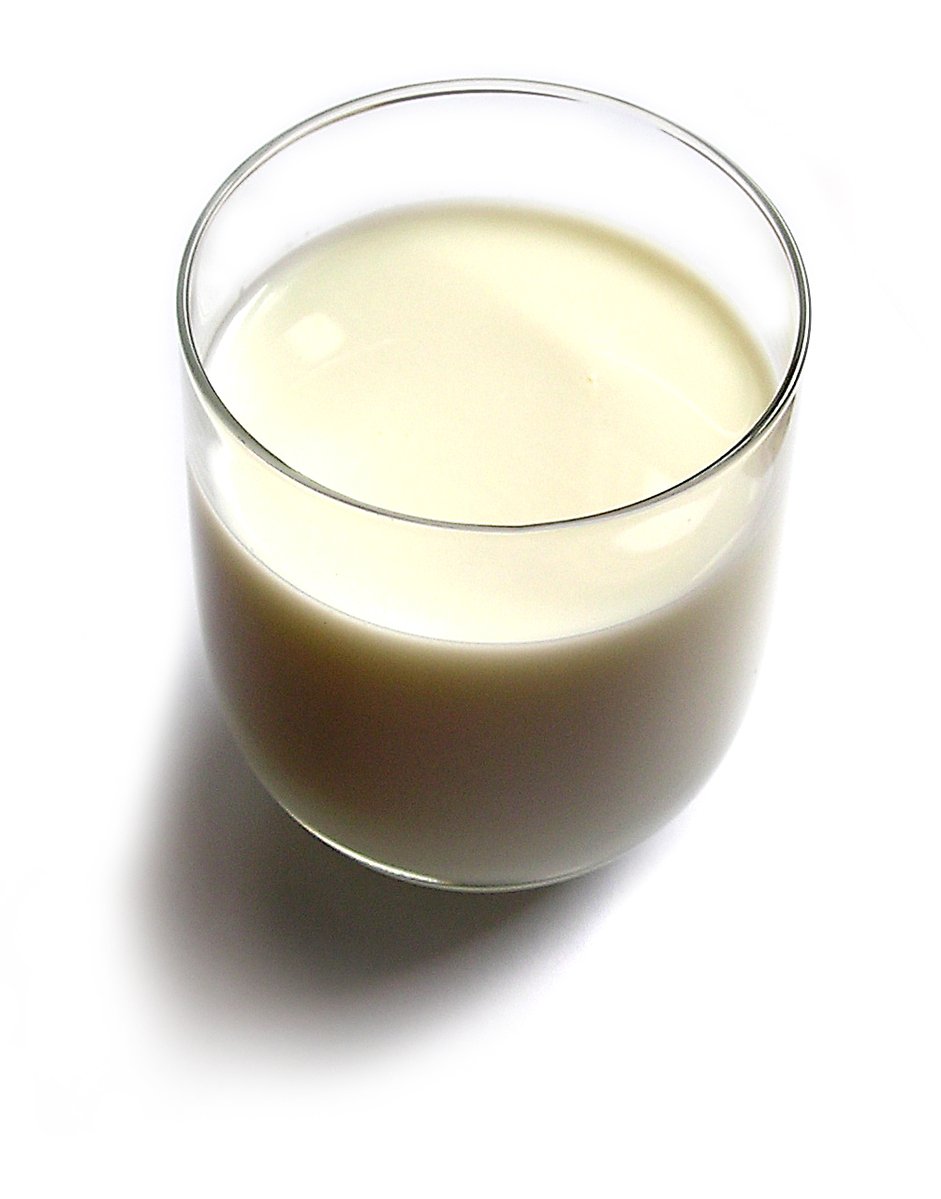 a glass of milk sitting on top of a white surface
