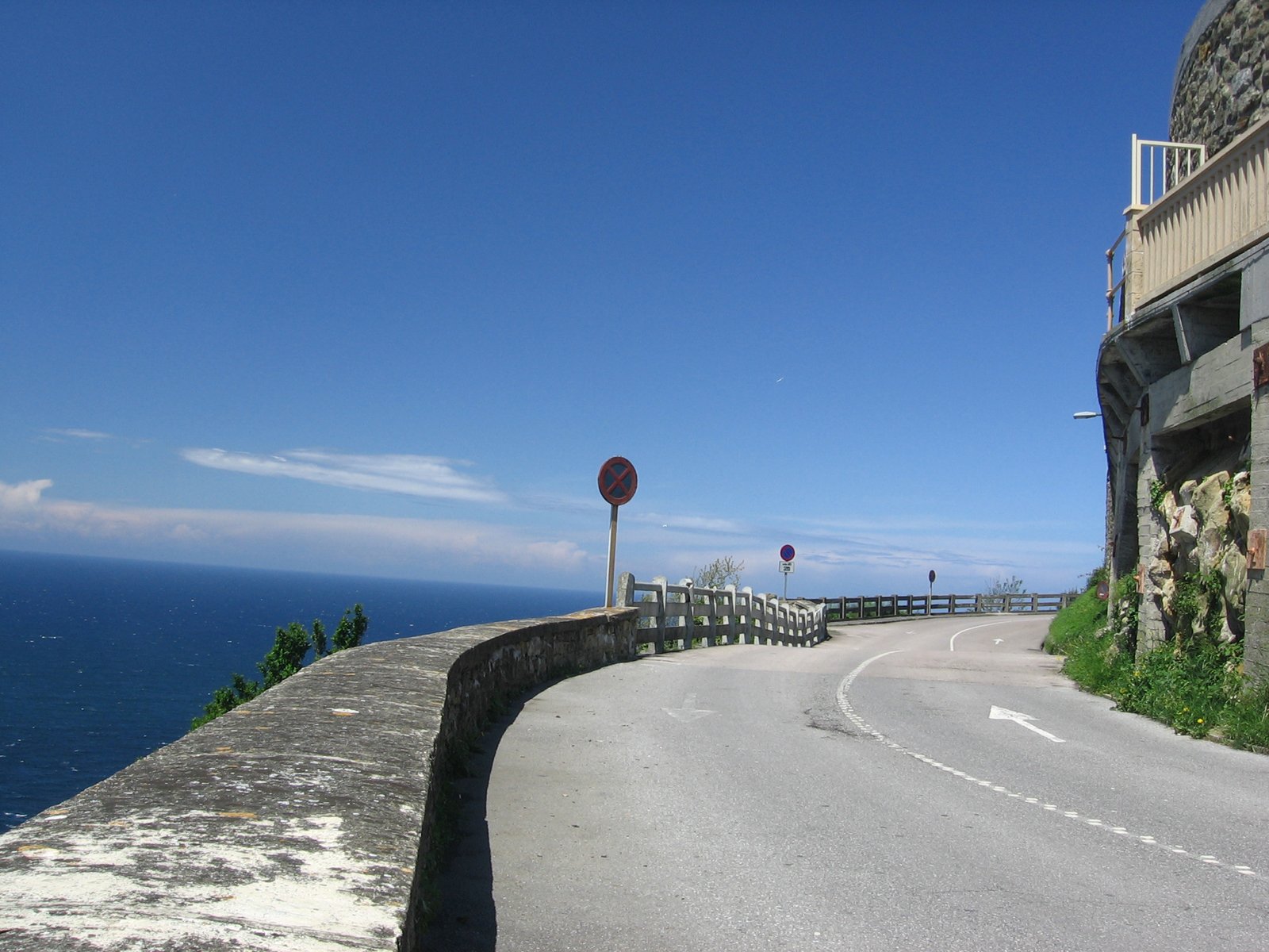 a winding street near the ocean with some trees