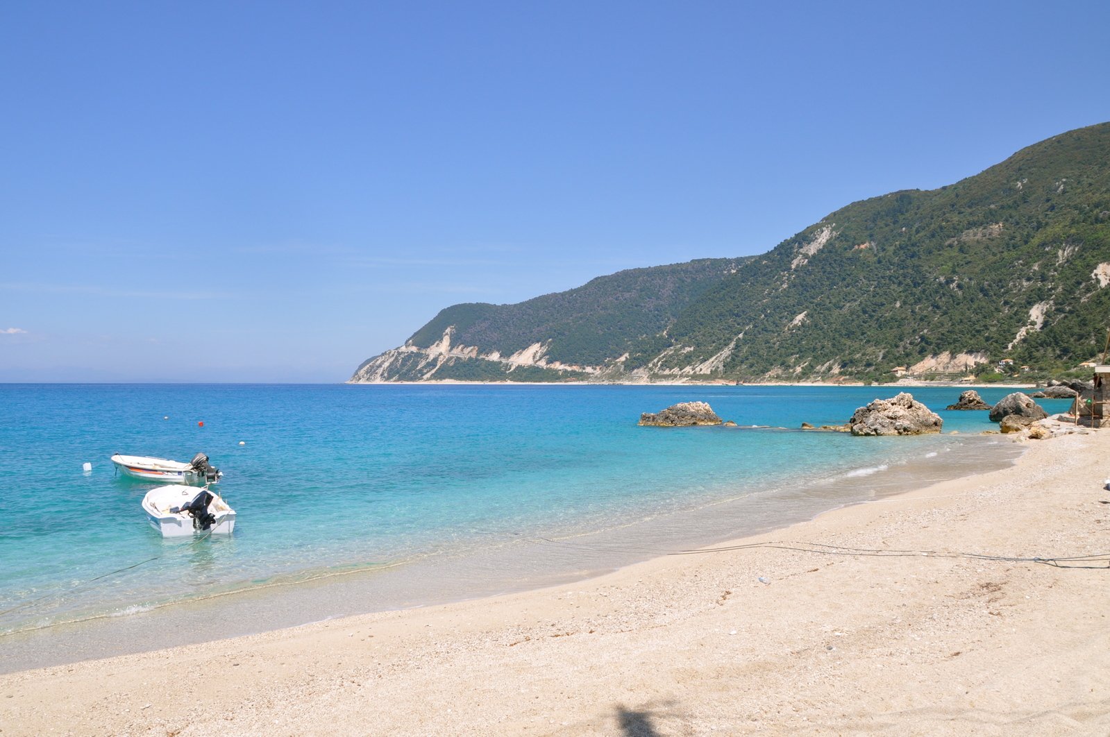 a beach with boats and mountains in the distance