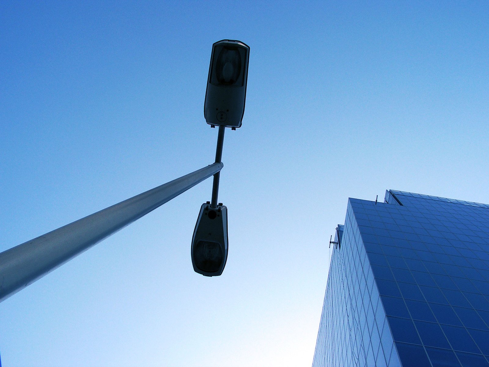 two traffic signals standing next to a tall building