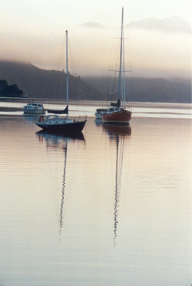 three boats are out on the water with a cloudy sky behind them