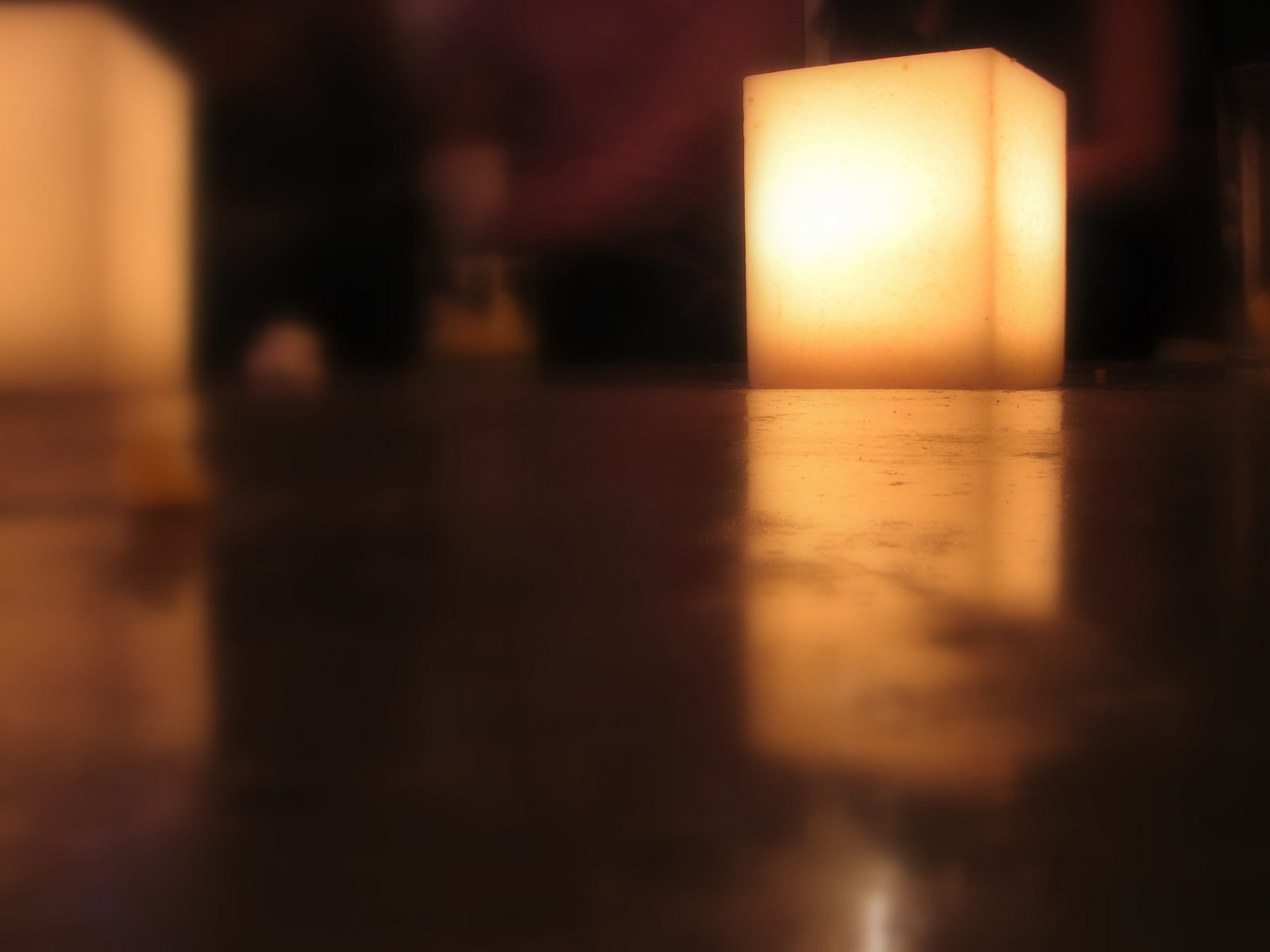 two square candle lights sit on the ground