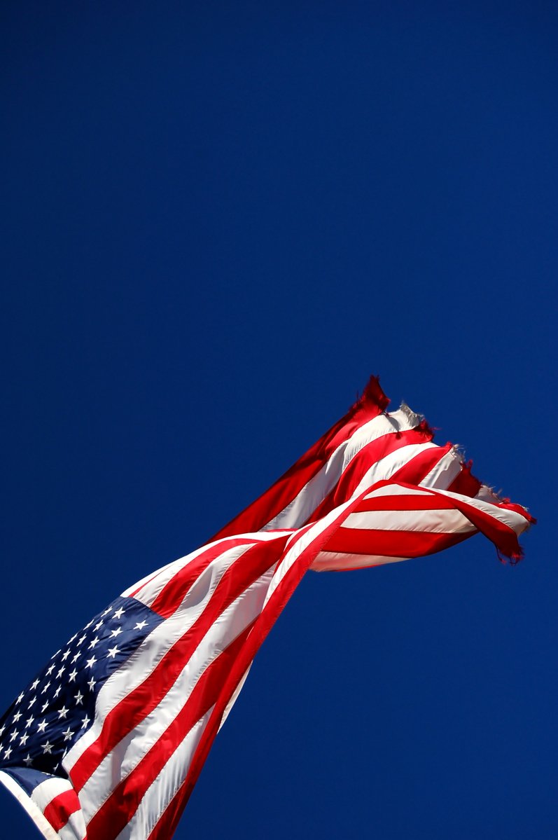 a group of american flags are seen against a blue sky