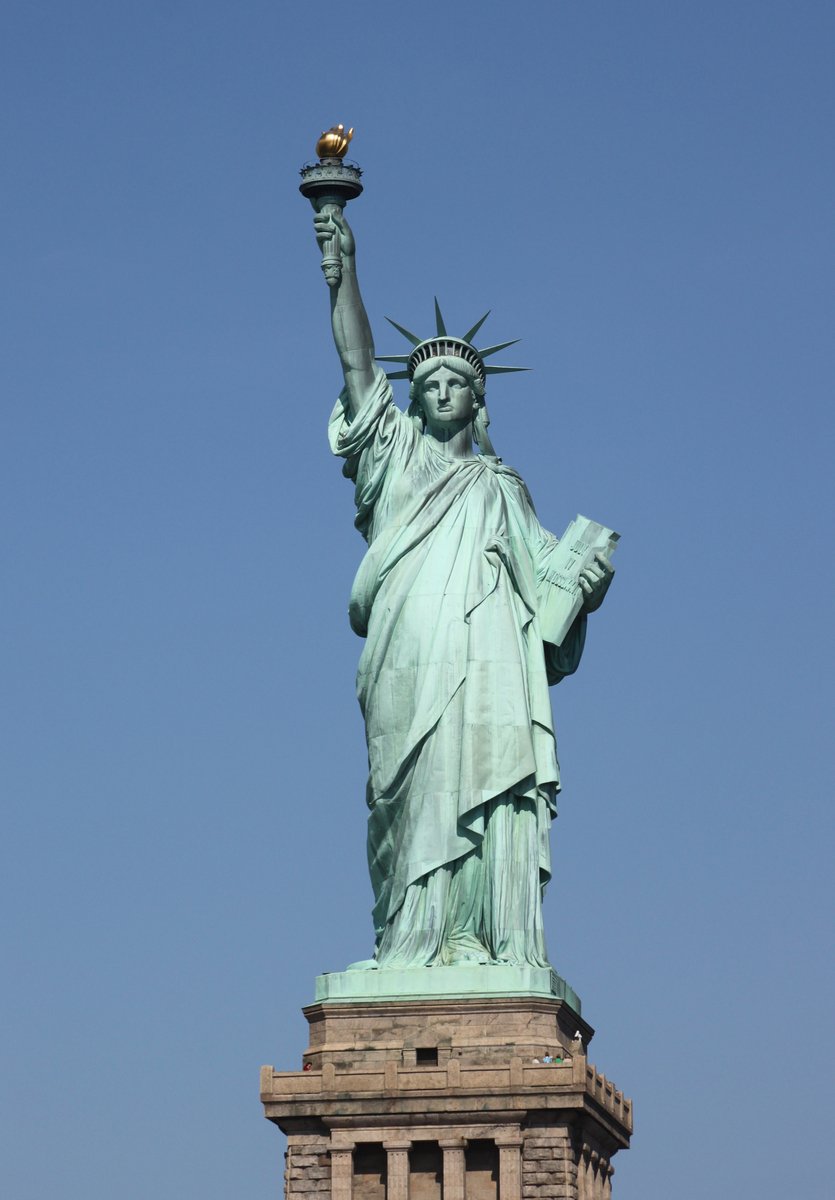 the statue of liberty stands in front of the clear blue sky