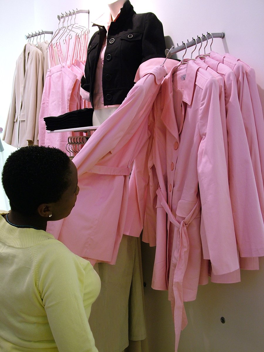 a woman looking at a display of pink shirts