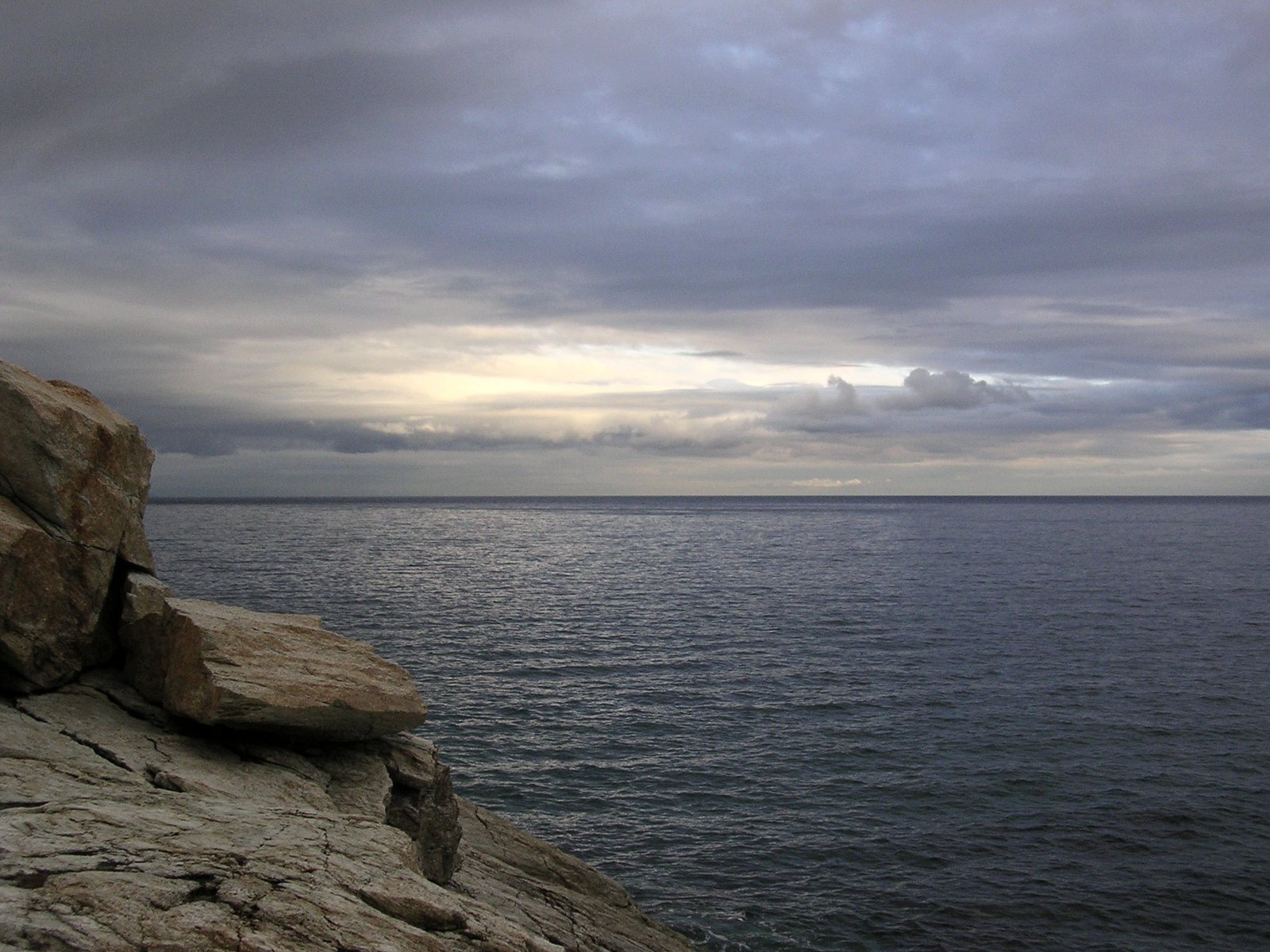 large rocks sitting on top of a cliff near the water