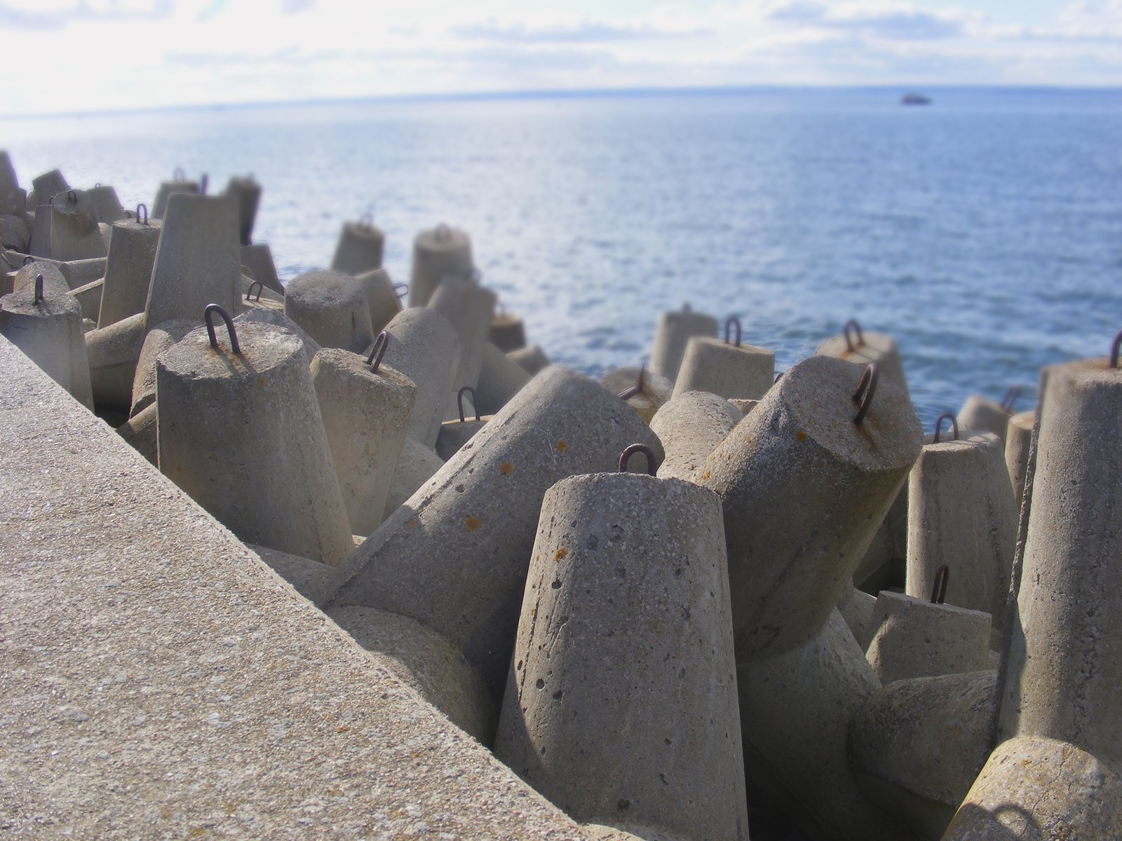 cement blocks on the ground by water with blue sky in background