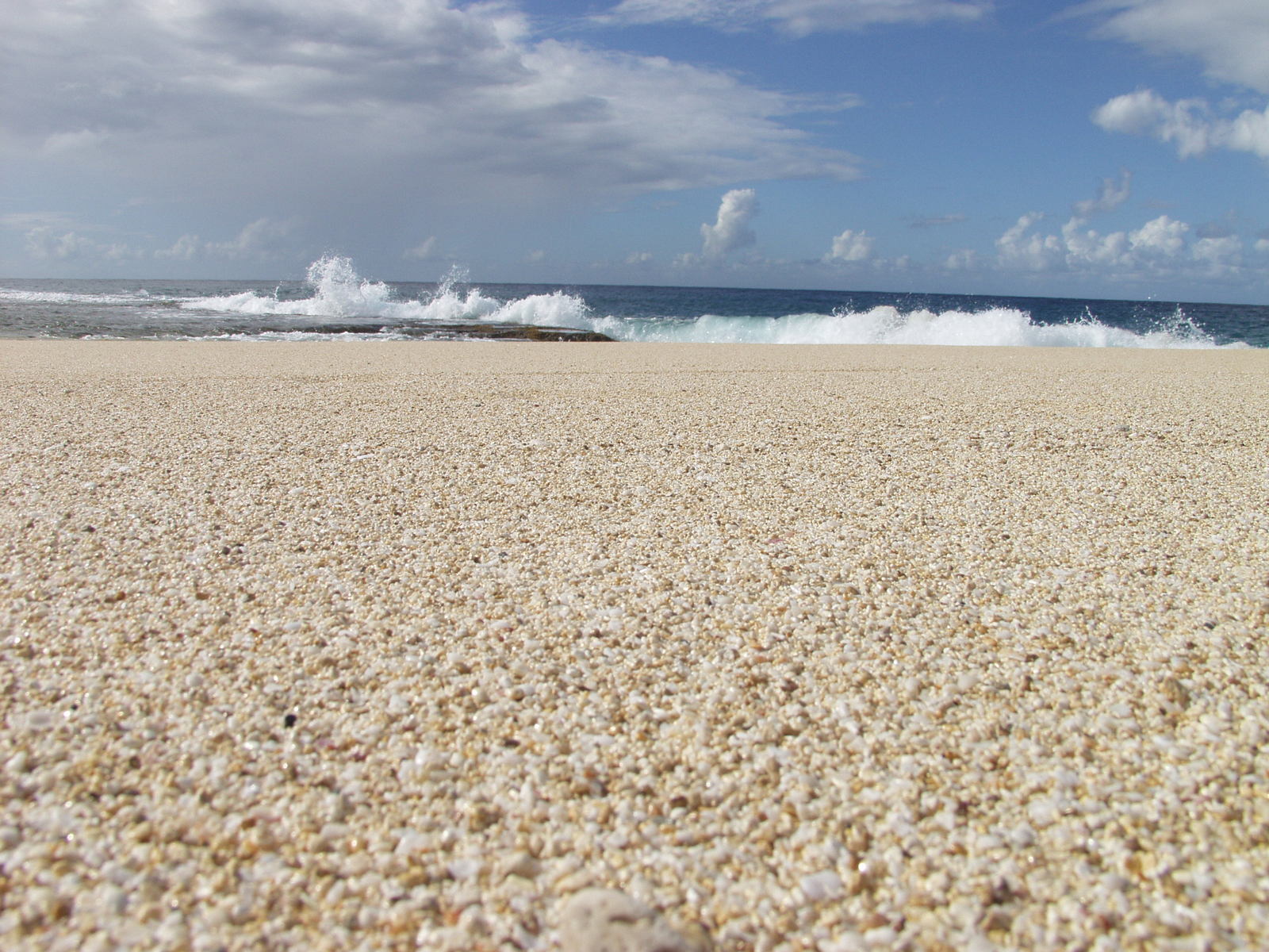 a sand covered beach with waves coming in