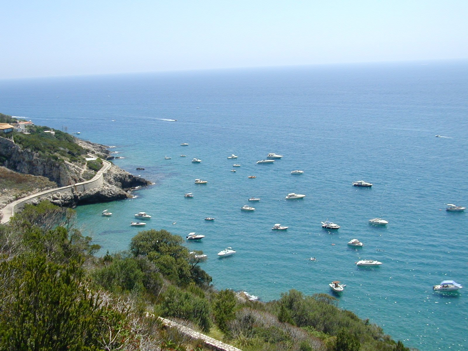 boats are in the water near a rocky coastline